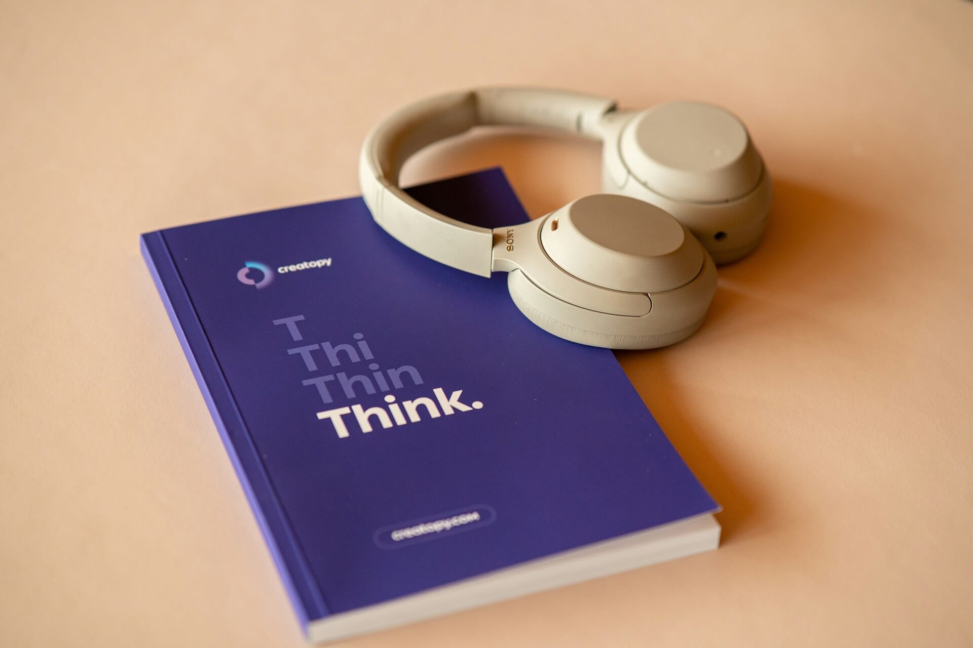 livre avec une couverture bleu et un casque audio posé à coté